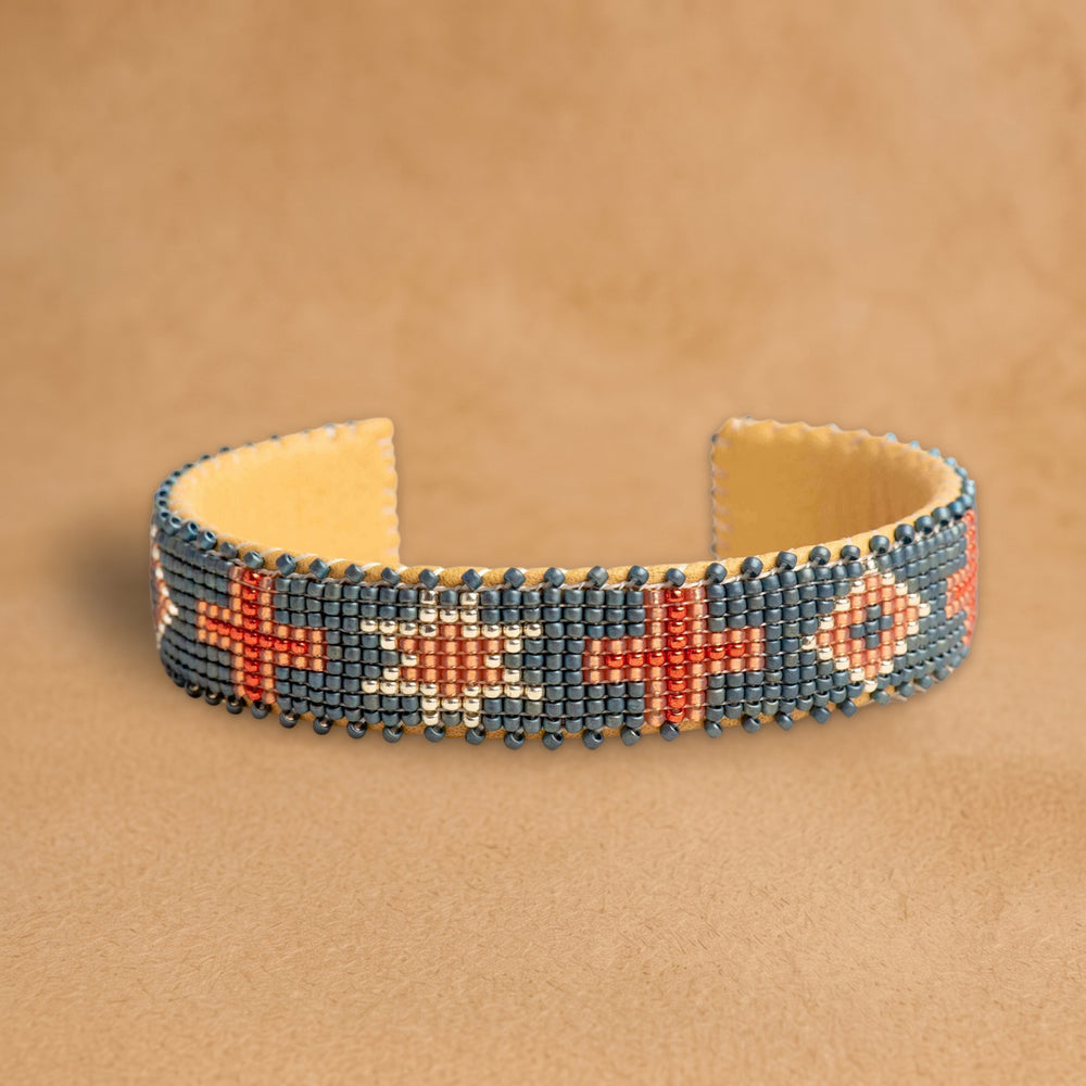 Belle Small beaded cuff, slate blue with coral crosses, an eight-point star and diamonds, handloomed by Navajo artisans in New Mexico