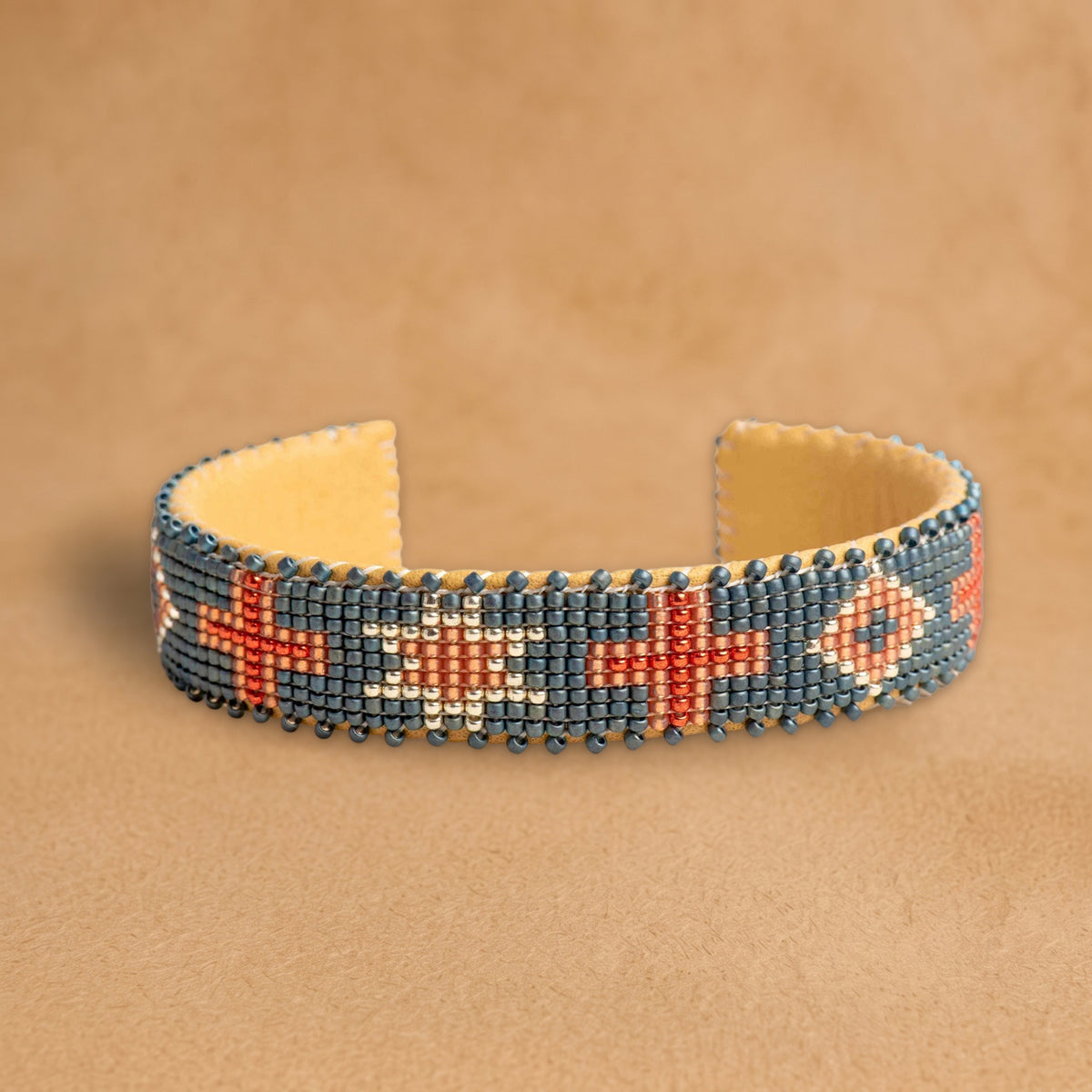 Belle Small beaded cuff, slate blue with coral crosses, an eight-point star and diamonds, handloomed by Navajo artisans in New Mexico